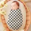 Sleeping Baby Swaddled In A Black And White Checkered Blanket.
