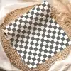 A Roll Of Dark Gray And White Checkered Wrapping Paper On A Woven Placemat.