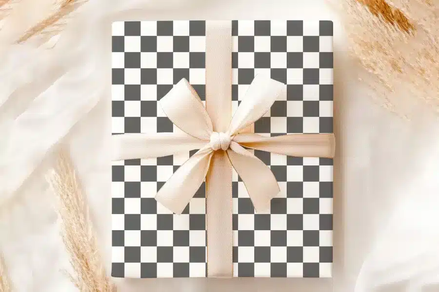 A Gift Box With A Black And White Checkered Pattern And A Beige Ribbon.