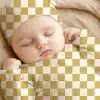 Sleeping Baby Wearing A Mustard Yellow And White Checkered Outfit.