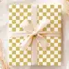 A Gift Box With A Gold And White Checkered Pattern And A Beige Ribbon.