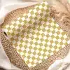 A Roll Of Mustard Yellow And White Checkered Wrapping Paper On A Woven Mat.