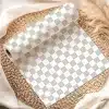 A Roll Of Gray And White Checkered Wrapping Paper Unfurling On A Woven Placemat.