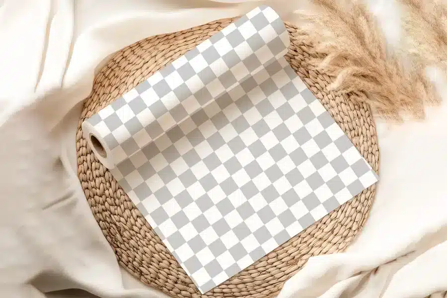 A Roll Of Gray And White Checkered Wrapping Paper Unfurling On A Woven Placemat.