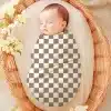 Sleeping Baby Swaddled In A Checkered Receiving Blanket Inside A Wicker Basket.