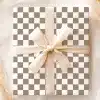 A Gift Box With A Taupe And White Checkered Pattern And A Large Beige Bow.