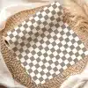 A Roll Of Brown And White Checkered Wrapping Paper On A Woven Placemat.