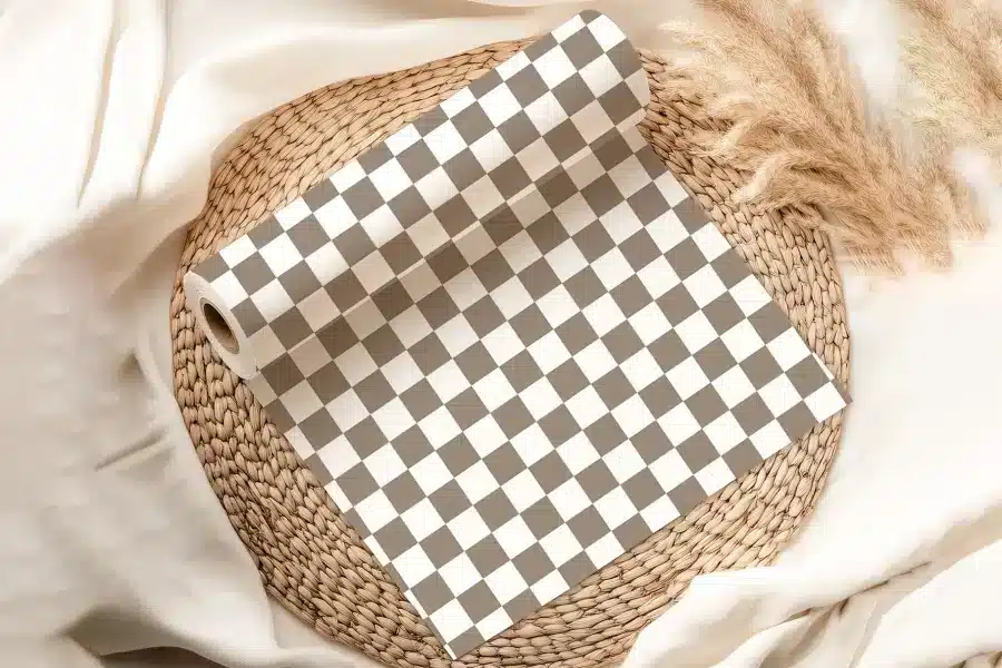 A Roll Of Brown And White Checkered Wrapping Paper On A Woven Placemat.