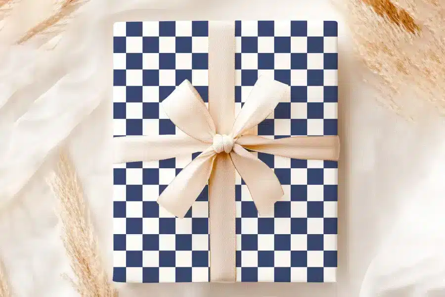 A Gift Box With A Navy Blue And White Checkered Pattern, Tied With A Beige Ribbon.