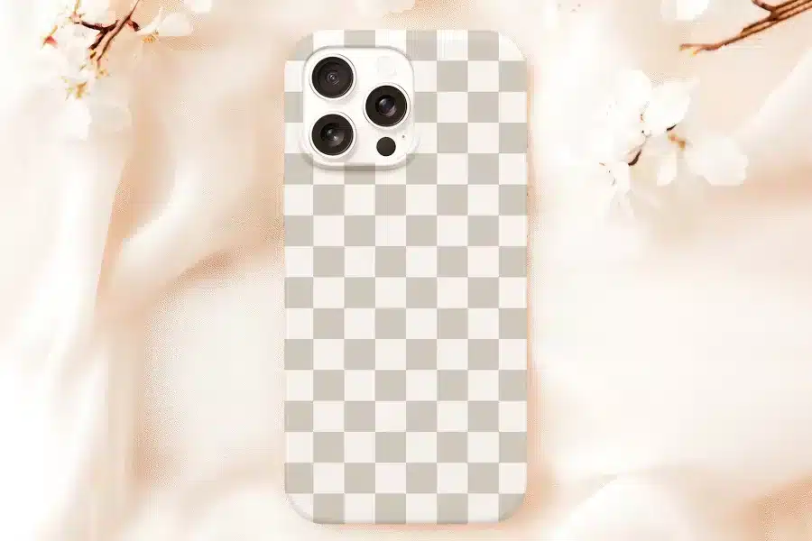 A Beige Phone Case With A Checkered Pattern Sits On A Peach-Colored Fabric.