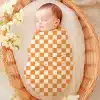 Sleeping Baby Swaddled In An Orange And White Checkered Blanket.