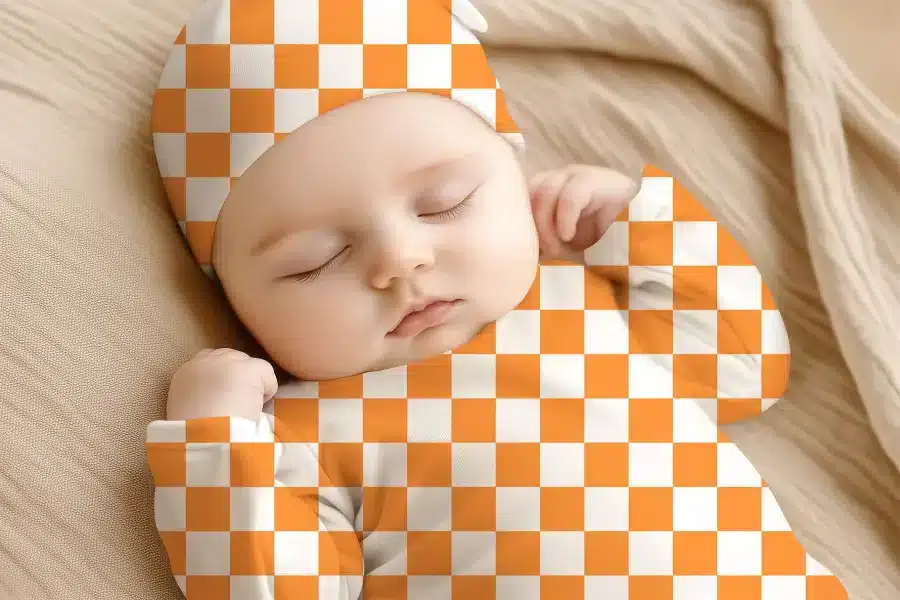 Sleeping Baby Wearing An Orange And White Checkered Outfit.