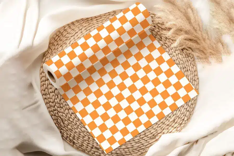 Orange And White Checkered Wrapping Paper Roll On A Woven Mat.