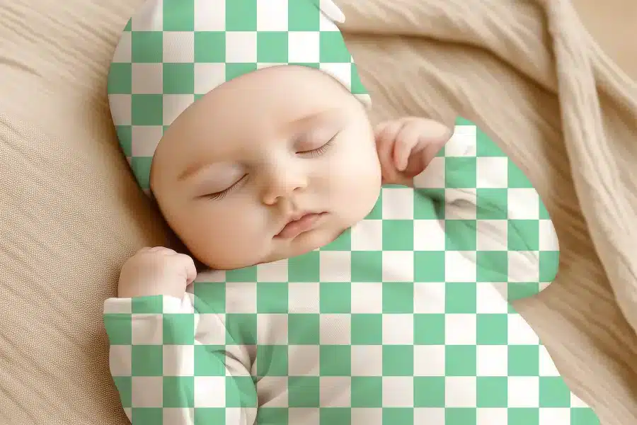 Sleeping Baby Wearing A Mint Green And White Checkered Onesie And Hat.