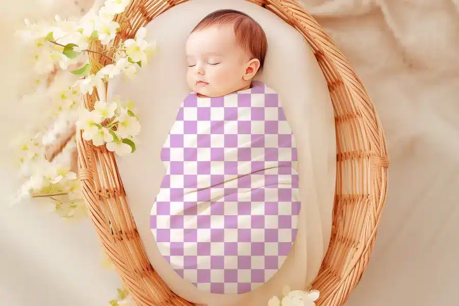 Sleeping baby wrapped in a lavender and white checkered swaddle.