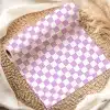 A Roll Of Lavender And White Checkered Wrapping Paper On A Woven Placemat.