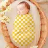 Sleeping Baby Swaddled In A Yellow And White Checkered Blanket.