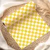 Roll Of Yellow And White Checkered Wrapping Paper On A Woven Placemat.