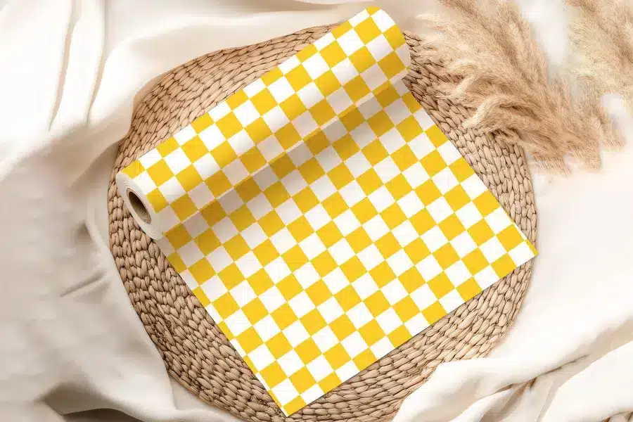Roll Of Yellow And White Checkered Wrapping Paper On A Woven Placemat.