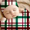 Sleeping Baby Wearing A Red, Green, And White Plaid Outfit.