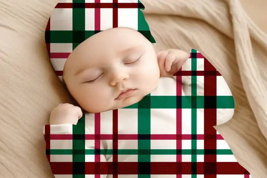 Sleeping Baby Wearing A Red, Green, And White Plaid Outfit.