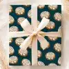 A Gift Wrapped In Teal Paper With A Repeating Pattern Of Cinnamon Rolls, Tied With A Beige Ribbon.