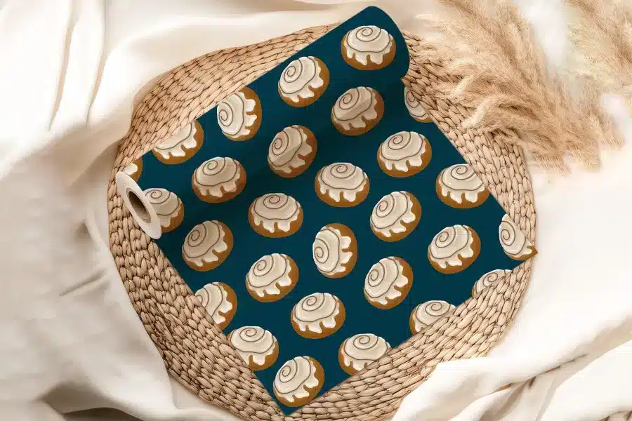A Roll Of Dark Teal Wrapping Paper With A Repeating Pattern Of Cinnamon Rolls.