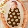 Sleeping Baby Swaddled In A Cinnamon Roll Patterned Wrap.