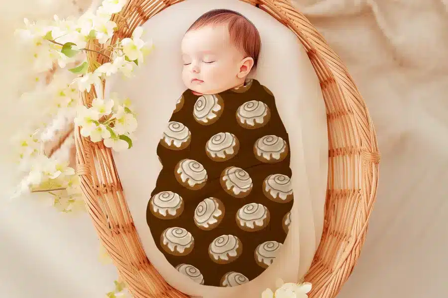 Sleeping baby swaddled in a cinnamon roll patterned wrap.