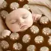 Sleeping Baby Wearing A Cinnamon Roll Patterned Outfit.