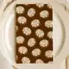A Brown Napkin With A Repeating Pattern Of Cinnamon Rolls Sits On A White Plate.