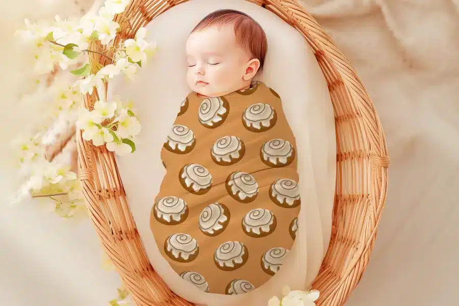 Sleeping baby swaddled in a cinnamon roll patterned wrap.