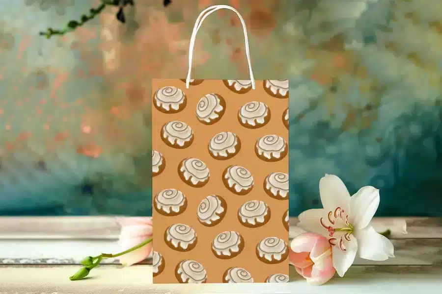 A Tan Paper Gift Bag Decorated With A Pattern Of Cinnamon Rolls.
