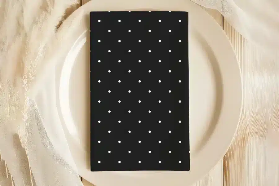 Black Napkin With White Polka Dots On A Beige Plate.