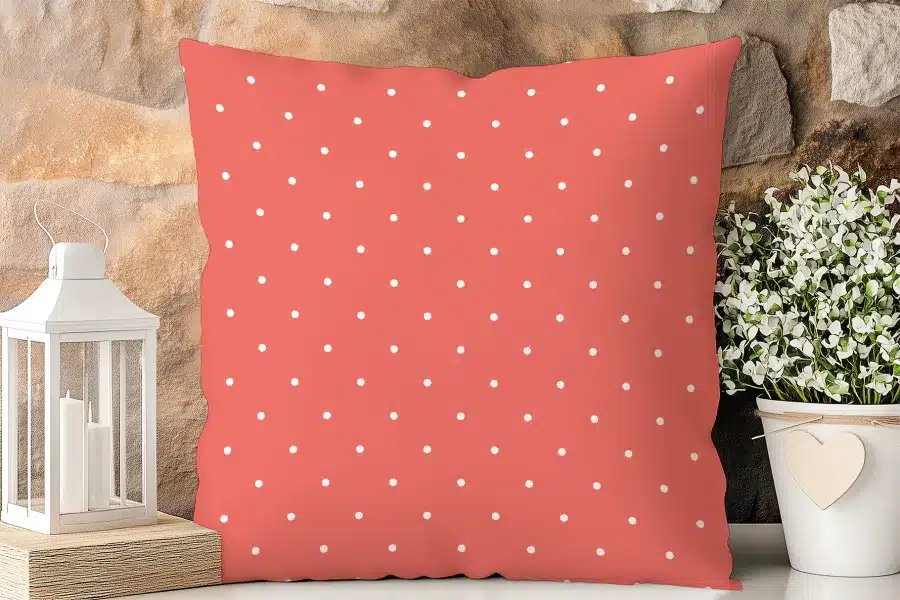 Coral-Colored Pillow With A White Polka Dot Pattern.