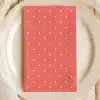 Coral-Colored Napkin With White Polka Dots On A White Plate.