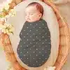 Sleeping Baby Swaddled In A Gray Polka Dot Wrap Inside A Wicker Basket.