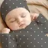 Sleeping Baby Wearing A Gray Polka Dot Hat And Outfit.