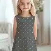 A Young Girl In A Gray Polka Dot Dress.