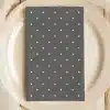 Dark Gray Napkin With White Polka Dots On A Beige Plate.