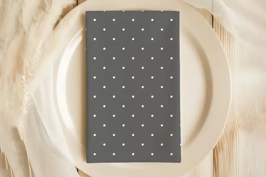 Dark Gray Napkin With White Polka Dots On A Beige Plate.
