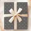 A Gray Gift Box With White Polka Dots And A Beige Ribbon.