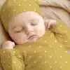 Sleeping Baby Wearing A Mustard Yellow Polka Dot Onesie And Matching Hat.