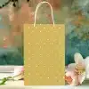 Mustard Yellow Gift Bag With White Polka Dots, Next To Pink Tulips And A White Lily.