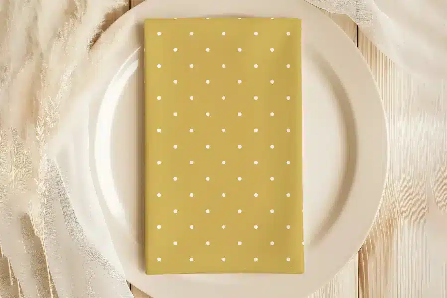 Mustard Yellow Napkin With White Polka Dots On A White Plate.