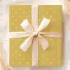A Mustard Yellow Gift Box With White Polka Dots, Tied With A Cream-Colored Ribbon.