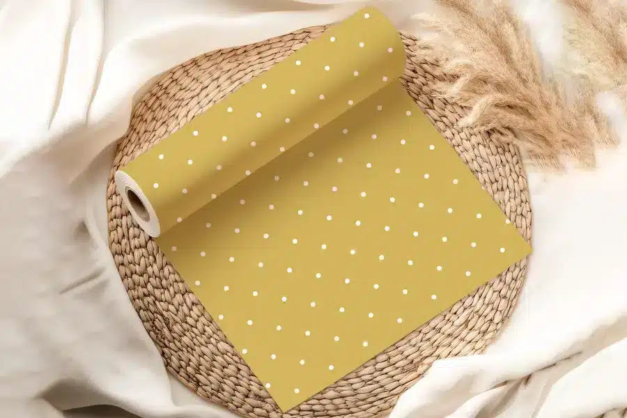 Mustard Yellow Wrapping Paper With White Polka Dots, Rolled On A Woven Mat.