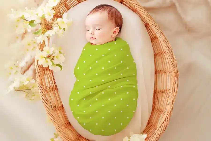 Sleeping baby swaddled in a lime green polka dot wrap.
