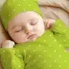 Sleeping Baby Wearing A Lime Green Polka Dot Onesie And Matching Hat.