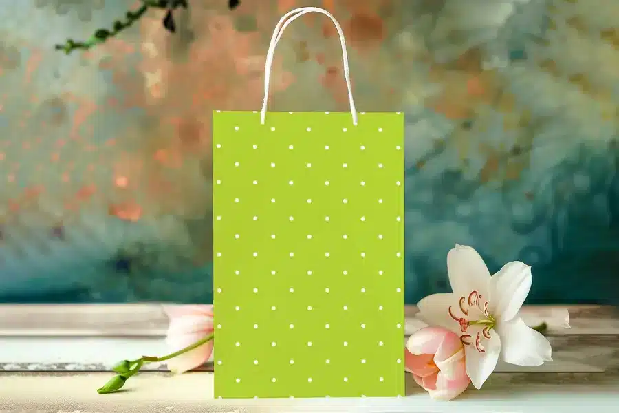 Light Green Gift Bag With White Polka Dots, Next To Pink Tulips And A White Lily.
